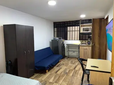 a small room with a blue couch and a kitchen at Coliving Belen Malibu in Medellín