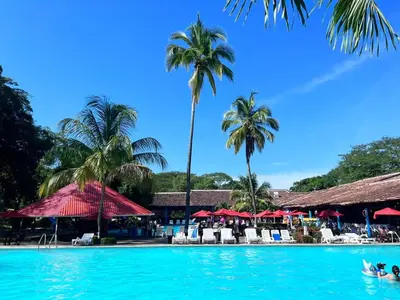 a pool at a resort with palm trees and umbrellas at Hostería Florida Tropical in Santa Fe de Antioquia