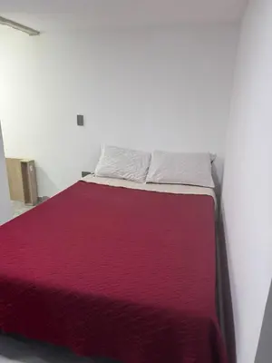 a bed in a white room with a red blanket at Villa Loreto Aparta estudio 202 in Medellín