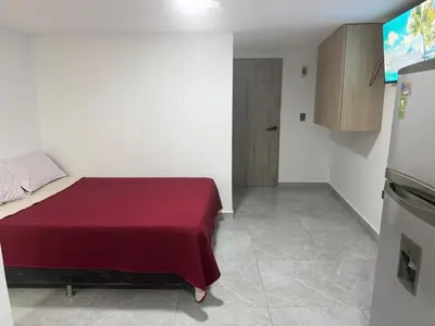 a bedroom with a bed with a red blanket on it at Villa Loreto Aparta estudio 202 in Medellín