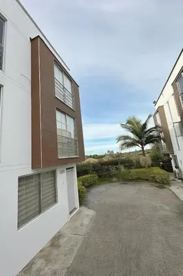 a building with a parking lot next to a palm tree at Casa en Marinilla cerca a guatape y el peñol in Marinilla