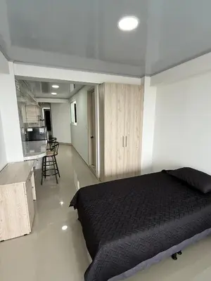 a bedroom with a black bed and a kitchen at Hotel El Samán in Quinchía