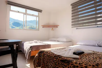 a room with two beds and a table and a window at Hotel Plaza Centro Cocorná in Cocorná