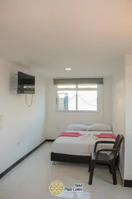 a bedroom with a bed and a chair in it at Hotel Plaza Centro Cocorná in Cocorná