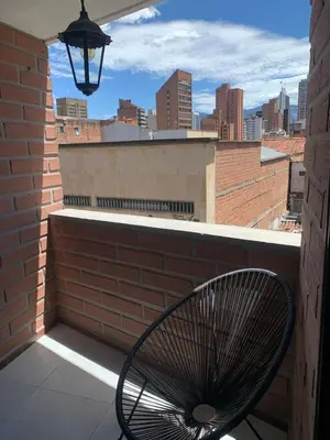 a chair on a balcony with a view of a city at Natural charm in Medellín in Medellín