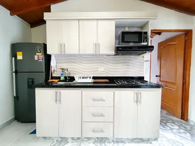 a kitchen with white cabinets and a microwave and a refrigerator at Acogedor apartamento cerca al tranvía 301 in Medellín