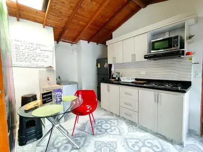 a kitchen with a table and a red chair at Acogedor apartamento cerca al tranvía 301 in Medellín
