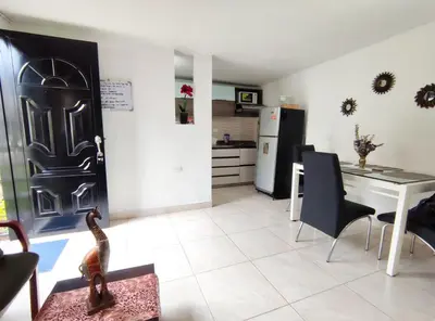 a kitchen and dining room with a table and a door at Acogedor apartamento cerca al tranvía 201 in Medellín