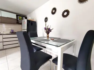 a dining room table with black chairs and mirrors on the wall at Acogedor apartamento cerca al tranvía 201 in Medellín