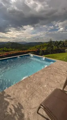 a swimming pool with a chair sitting next to it at Escápate Sonata in Chinchiná