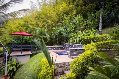 a garden with a pool and a red umbrella at Hermosa Casa y Cabañas en Barbosa, Antioquia in Barbosa
