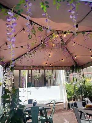 a patio with tables and chairs and purple flowers at Casa La Morada in Medellín