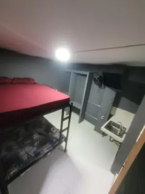 a small room with a red bed and a television at Dulce Hogar Aparta Hotel in Medellín