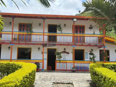 a house with red and yellow windows and bushes at Hostería El Paraíso in Jardin