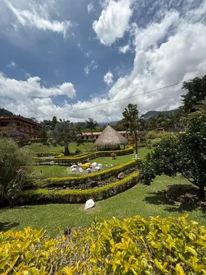a garden with a thatched building in the background at Hostería El Paraíso in Jardin
