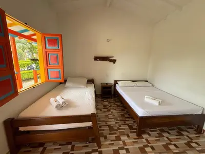 two beds in a room with a window at Hostería El Paraíso in Jardin