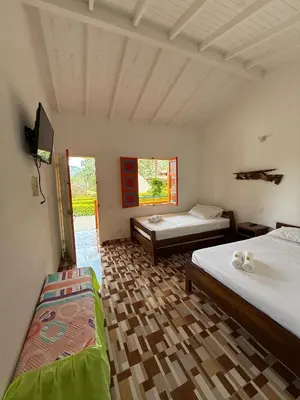a room with two beds and a tv in it at Hostería El Paraíso in Jardin