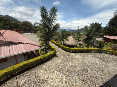 a walkway next to a resort with palm trees at Hostería El Paraíso in Jardin