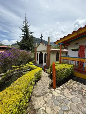a church with a cross and flowers in front of it at Hostería El Paraíso in Jardin