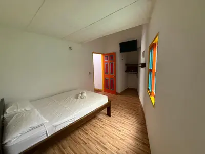 a bedroom with a white bed and a red door at Hostería El Paraíso in Jardin
