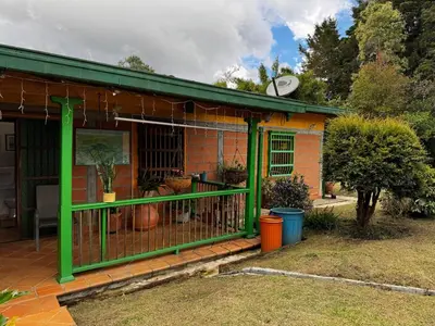 a house with a green fence in a yard at Magical farmhouse near Arví Park in Mazo