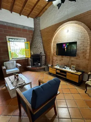 a living room with a fireplace and a tv at Magical farmhouse near Arví Park in Mazo