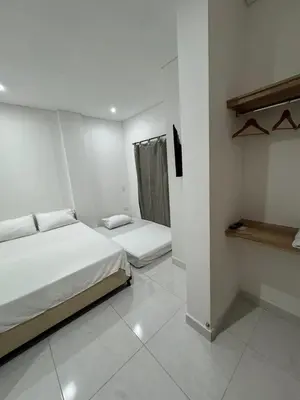 a white room with two beds and a shelf at Habitaciones en Doradal 202 in Doradal