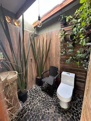 a bathroom with a toilet and a chair and plants at Finca El Encanto in Jericó