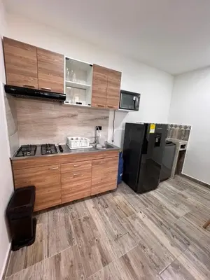 a kitchen with wooden cabinets and a black refrigerator at Meraki Urban Lofts in Quibdó