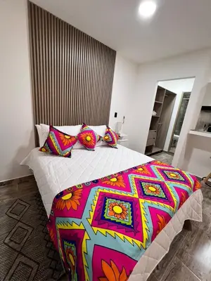 a bedroom with a large bed with colorful pillows at Meraki Urban Lofts in Quibdó