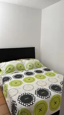 a bed with a black and green comforter at Cabaña San Jerónimo in San Jerónimo