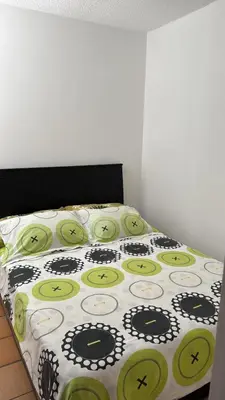 a bed with a black and green comforter at Cabaña ciudadela premium San Jerónimo in San Jerónimo