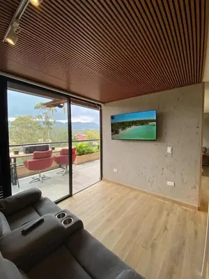 a living room with a couch and a television on a wall at San Telmo - Guatape with Hot Tube in Guatapé