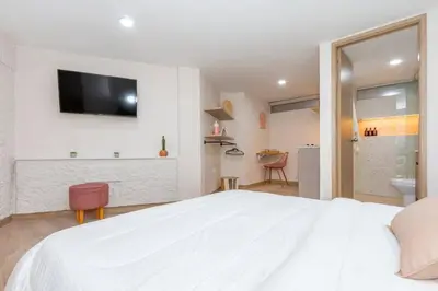 a bedroom with a white bed and a tv on a wall at Cozy Apt 4 -Laureles -AC- Smart Lock in Medellín