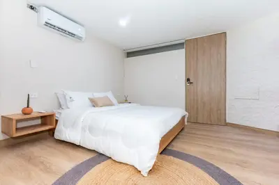 a white bedroom with a large bed and a door at Cozy Apt 4 -Laureles -AC- Smart Lock in Medellín