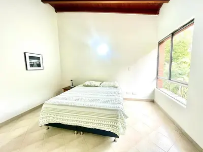 a bed in a white room with a large window at R301 Apartment close to Lleras park and Provenza in Medellín