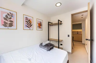 a bedroom with a white bed and some pictures on the wall at L301 4BR Lleras Park Apt Rooftop Jacuzzi AC in Medellín