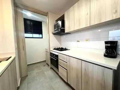 a kitchen with wooden cabinets and a stove top oven at SF501 Poblado Manila KBed Parking 247 security in Medellín