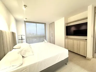 a white bedroom with a large bed and a television at SF501 Poblado Manila KBed Parking 247 security in Medellín