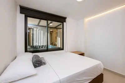a bedroom with a white bed with a large window at M501 Poblado Apt close to lleras park jacuzzi AC in Medellín