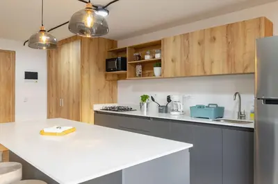 a kitchen with a white counter top and wooden cabinets at B1 Apt de 3 Alcobas en Poblado Provenza con Aire in Medellín