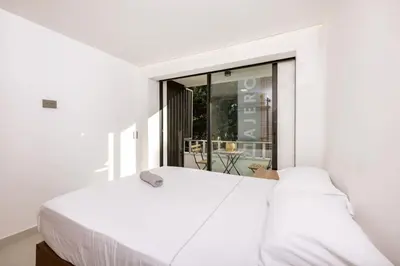 a bedroom with a white bed and a window at M54 Poblado 10BR 2 Apts with 2 Jacuzzis and AC in Medellín