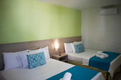 a hotel room with two beds with blue and white pillows at Hotel Aldea Plaza in Doradal