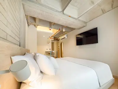 a bedroom with a white bed and a television at Hotel Once22 in Sabaneta