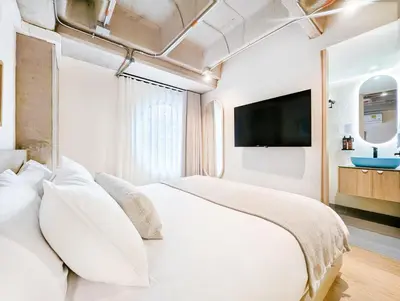 a bedroom with a large white bed with a flat screen tv at Hotel Once22 in Sabaneta