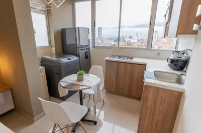 a small kitchen with a table and a refrigerator at Apartasuite Stay & Relax Itagui in Itagüí