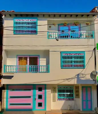 a white building with blue and pink doors and windows at Balcones Guatape Apartment in Guatapé
