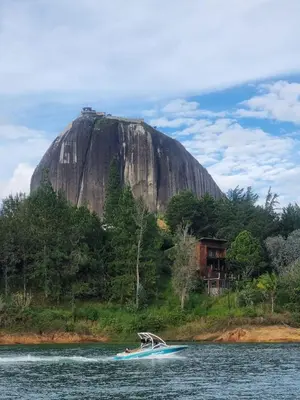 a boat in the water in front of a mountain at Balcones Guatape Apartment in Guatapé