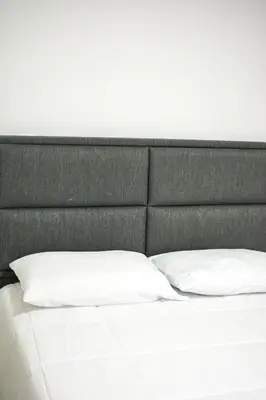 a bed with white pillows and a gray headboard at Balcones Guatape Apartment in Guatapé