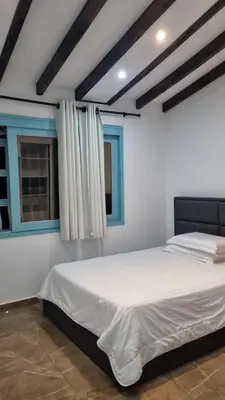 a bedroom with a white bed and two windows at Balcones Guatape Apartment in Guatapé